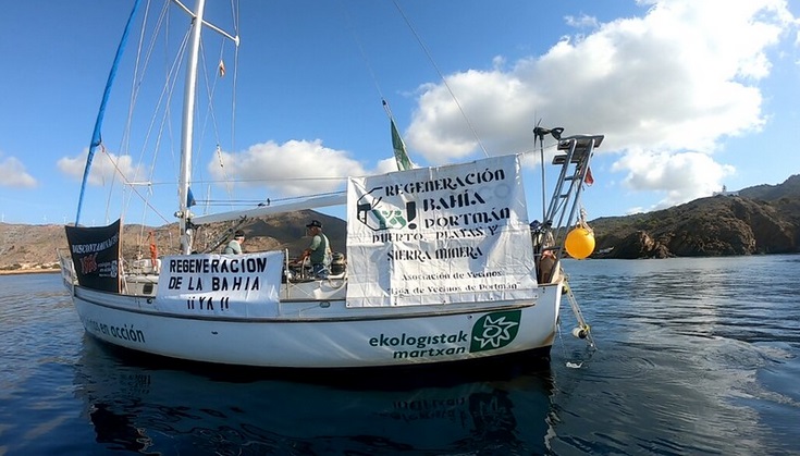 El Velero de Ecologistas en Acción despliega en Portmán pancartas para exigir su regeneración y contra la macro-terminal de El Gorguel